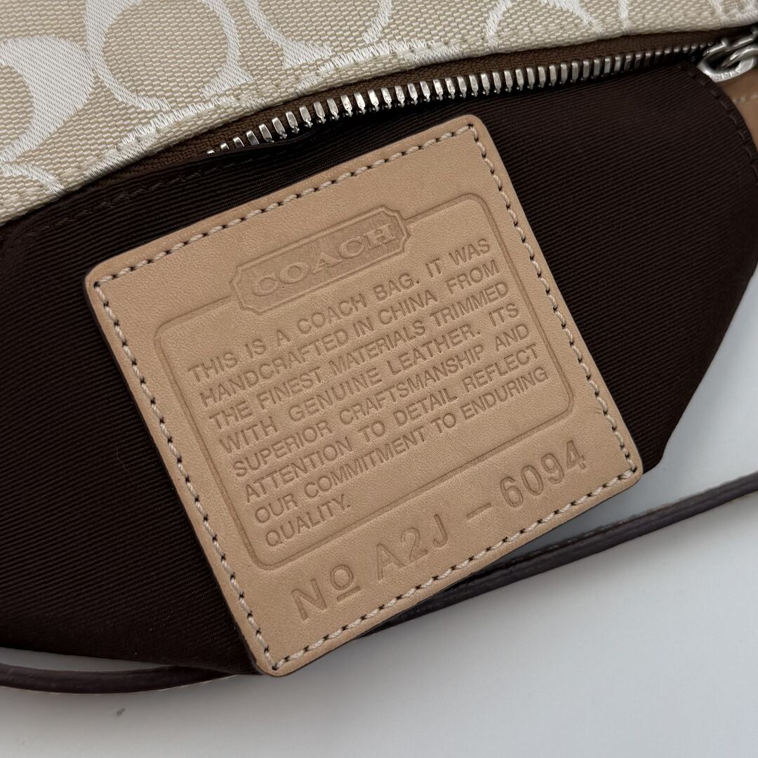 Close-up of a Coach bag with a leather label on a light background