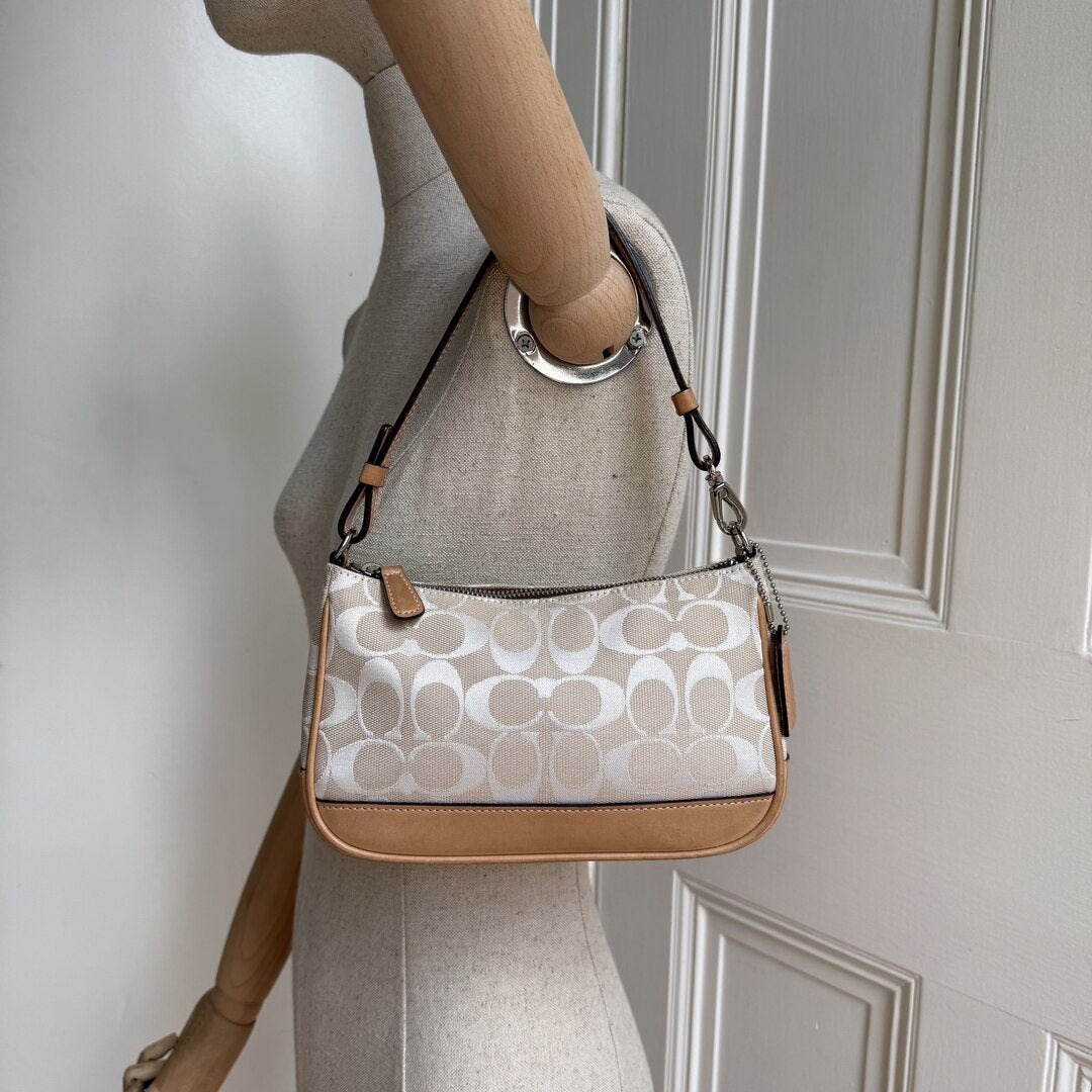 Patterned handbag with brown accents on a mannequin against a neutral background