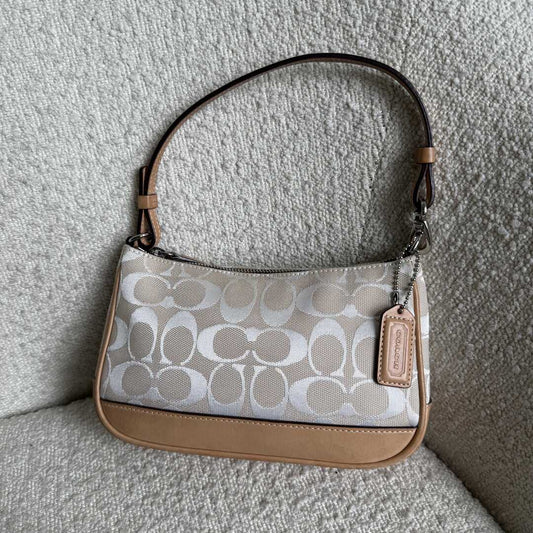 Coach handbag with beige and white pattern on a textured surface